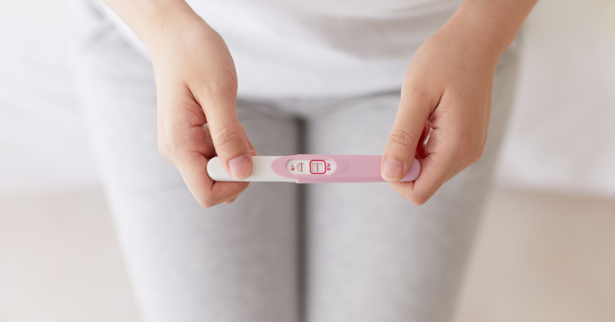 Woman in her 40s holding a positive pregnancy test, showing hope and success after tubal reversal at 40.